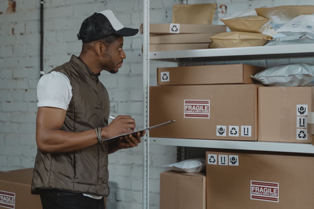 A warehouse worker checking shipping boxes and processing labels before customs entry