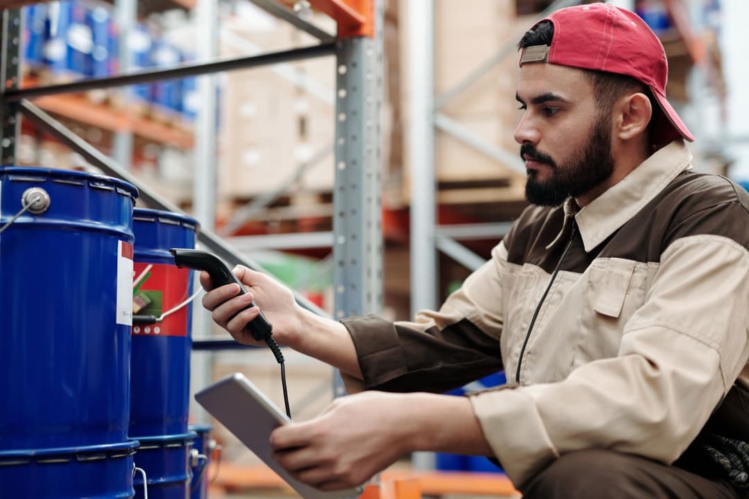 A warehouse worker scanning a product barcode to check its shipping label before an HS code lookup