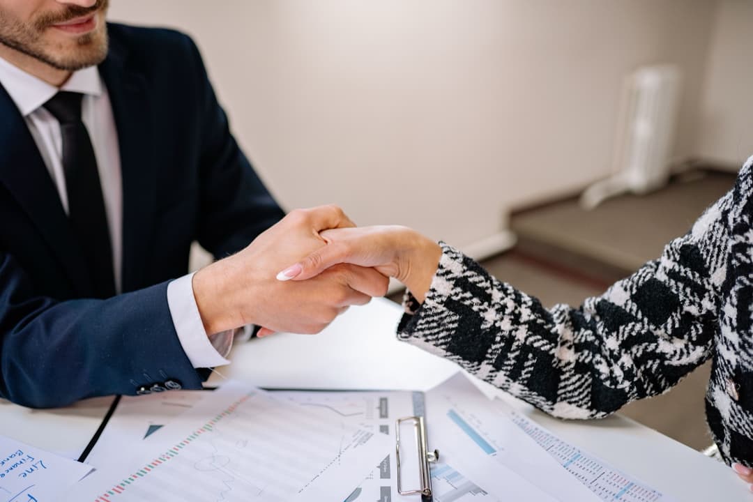 Business handshake over a signed contract on an office desk, representing the importer of record agreement between buyer and broker