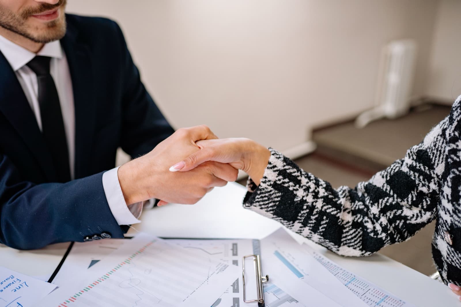 Business handshake over a signed contract on an office desk, representing the importer of record agreement between buyer and broker
