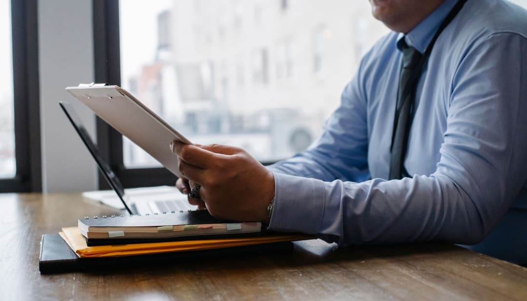 A businessman reviewing a document checklist on a clipboard, checking items against a list