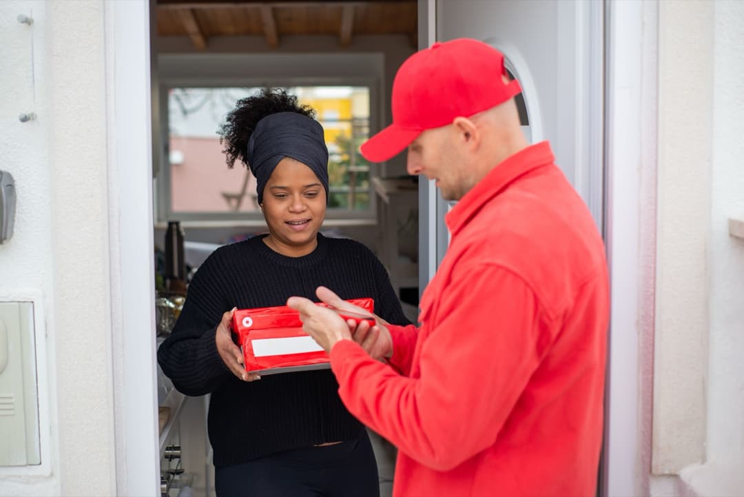 A delivery courier handing a parcel to a customer at their front door under DDP shipping terms